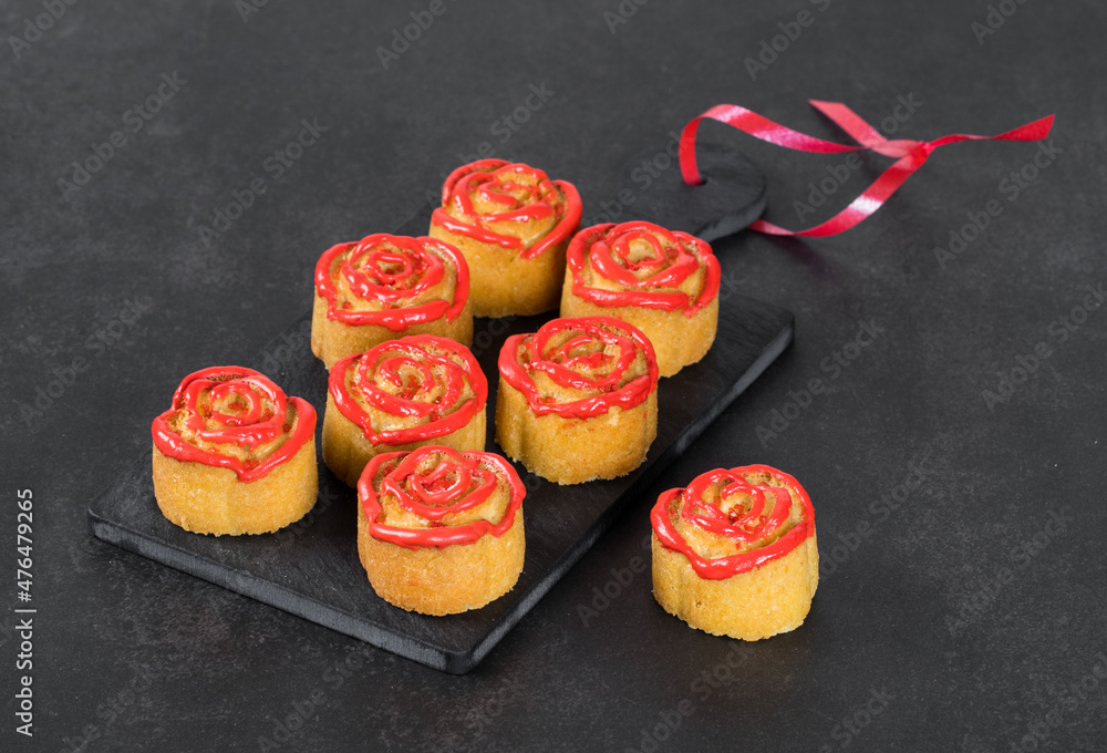 Dessert Cookies cakes in the shape of a rosebud with red icing sugar on a serving board on a dark gray background Dessert Cookies cakes in the shape of a rosebud with red icing sugar on a serving board on a dark gray background