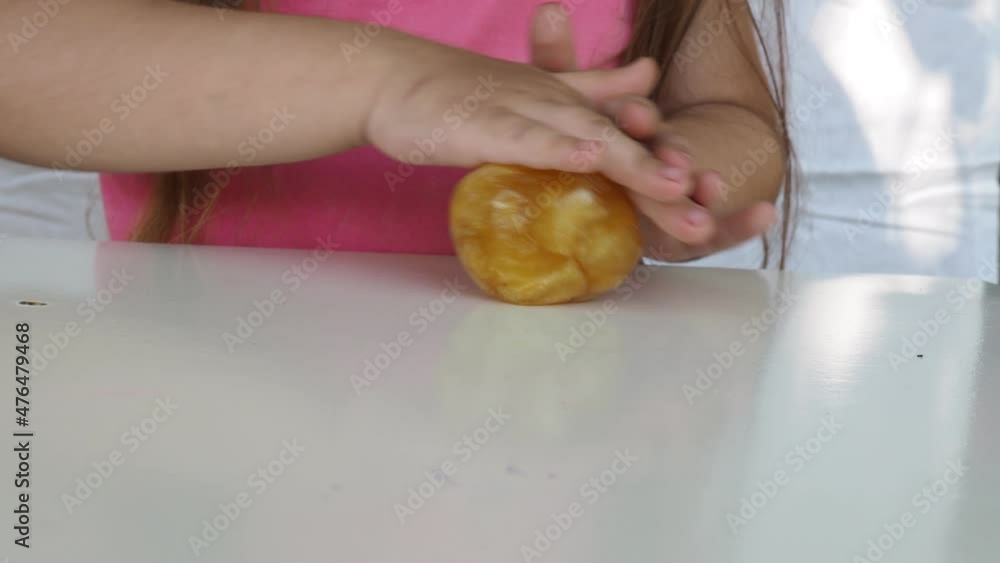 Kid Playing Hand Made Toy Called Slime. cute girl in a pink t-shirt plays with a yellow slime. contemporary creativity. stretching, scamming, modeling. Kid Playing Hand Made Toy Called Slime. cute girl in a pink t-shirt plays with a yellow slime. contemporary creativity. stretching, scamming, modeling.