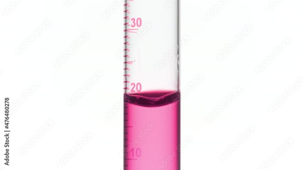 Drop of pink fluid is falling down into graduated cylinder with pink transparent fluid on white background | Abstract face care cosmetics formulation concept Drop of pink fluid is falling down into graduated cylinder with pink transparent fluid on white background | Abstract face care cosmetics formulation concept
