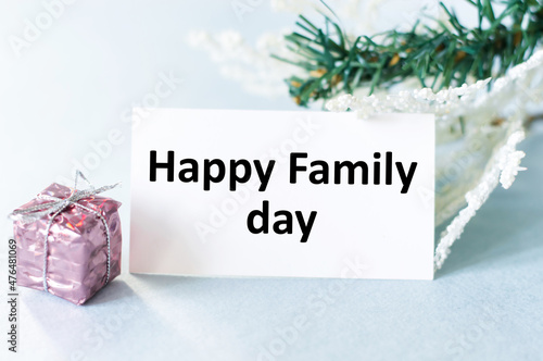 Happy family day text on the card next to the gift and spruce branches, family day