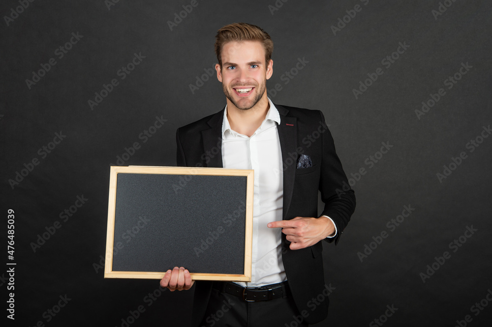 Happy teacher pointing finger at empty school blackboard copy space dark background, advertisement Happy teacher pointing finger at empty school blackboard copy space dark background, advertisement