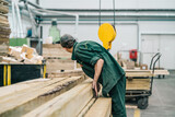 Woodworking worker in factory with stack of wood.