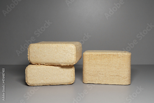 Pressed wood chip briquettes on a gray background. Solid fuels from coniferous and deciduous wood shavings