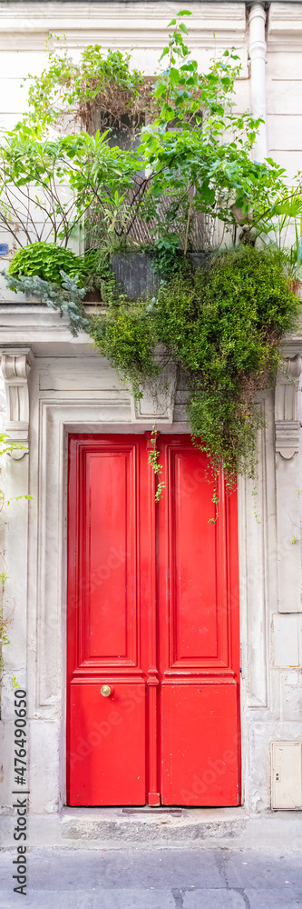 Paris, an ancient red door, beautiful facade with plants in the 11e arrondissement
