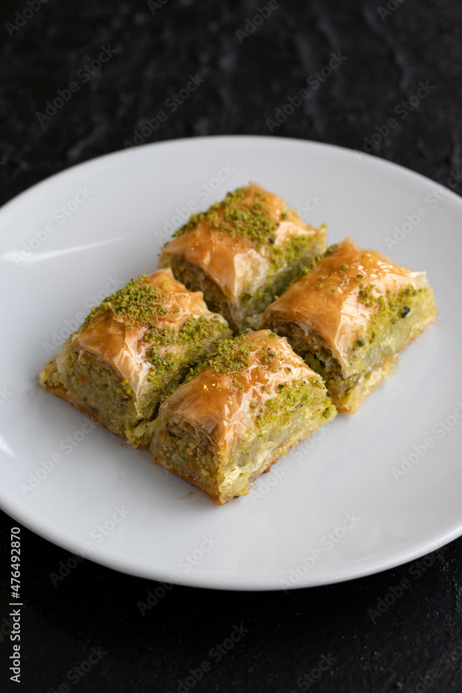 Pistachio baklava dessert on a dark background. Turkish sweet dessert concept. plate of pistachio baklava. sherbet sweet Mediterranean bakery. close up. selective focus.