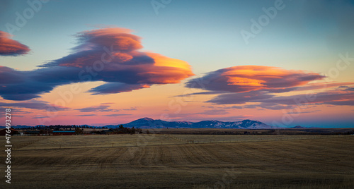 Colorful Lenticular clouds at sunset over mountain peaks