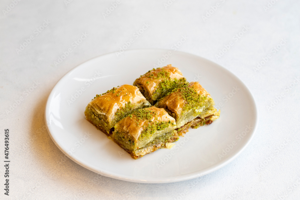 Pistachio baklava dessert on a white background. Turkish sweet dessert concept. plate of pistachio baklava. sherbet sweet Mediterranean bakery. close up. selective focus Pistachio baklava dessert on a white background. Turkish sweet dessert concept. plate of pistachio baklava. sherbet sweet Mediterranean bakery. close up. selective focus