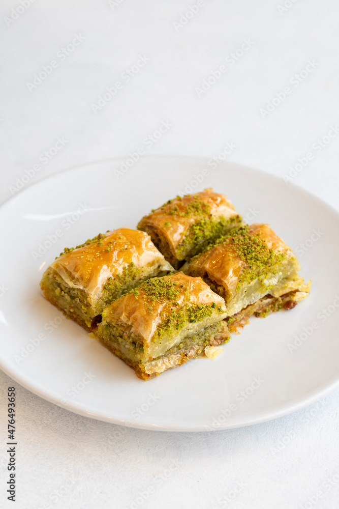 Pistachio baklava dessert on a white background. Turkish sweet dessert concept. plate of pistachio baklava. sherbet sweet Mediterranean bakery. close up. selective focus Pistachio baklava dessert on a white background. Turkish sweet dessert concept. plate of pistachio baklava. sherbet sweet Mediterranean bakery. close up. selective focus