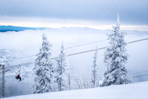 Winter landscape in Sheregesh ski resort in Russia  located in Mountain Shoriya  Siberia. Snow-covered fir trees on the background of mountains. Ski lift with skiers above speuce
