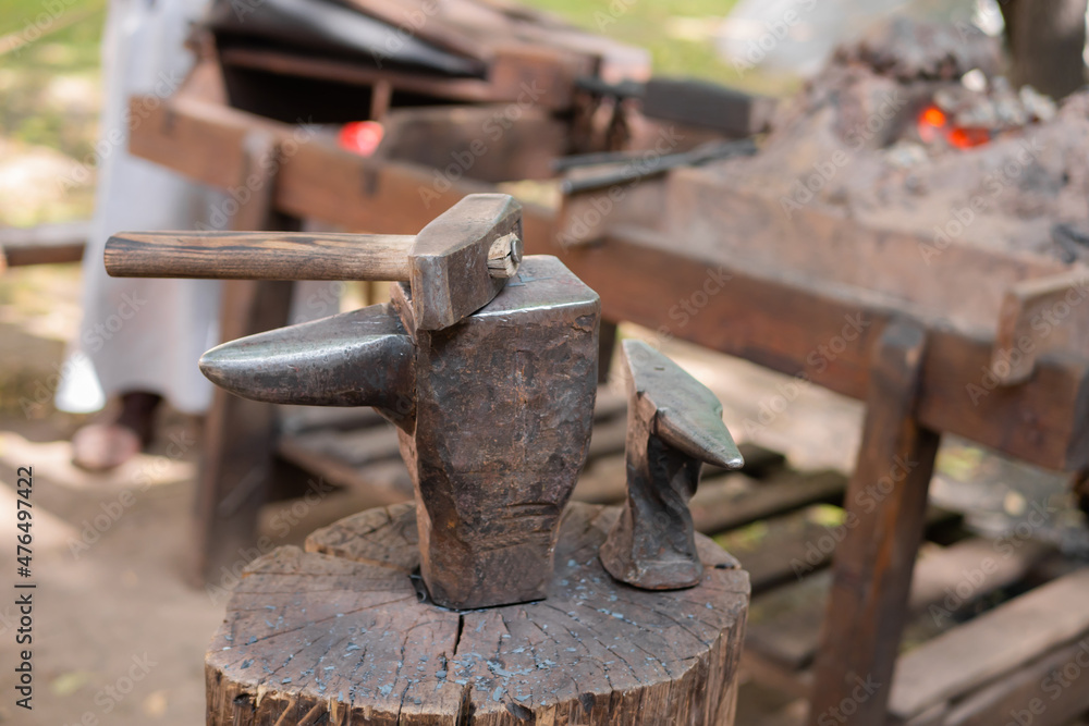 Hammer and blacksmith anvil at outdoor forge, workshop - close up, selective focus. Handmade, craftsmanship and blacksmithing concept Hammer and blacksmith anvil at outdoor forge, workshop - close up, selective focus. Handmade, craftsmanship and blacksmithing concept
