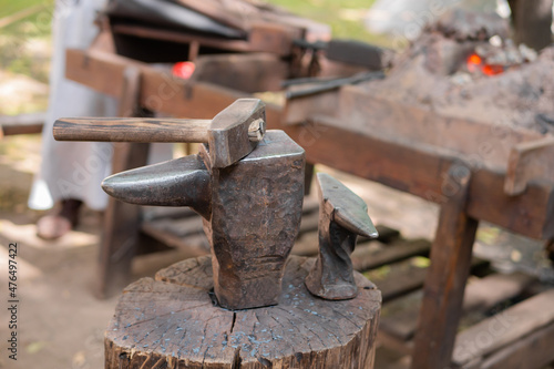 Hammer and blacksmith anvil at outdoor forge, workshop - close up, selective focus. Handmade, craftsmanship and blacksmithing concept