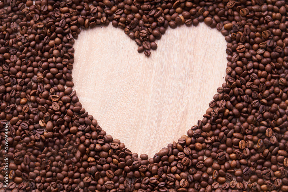 The coffee beans arranged in a heart shape on wooden background.Coffee beans are laid out in a heart shape The coffee beans arranged in a heart shape on wooden background.Coffee beans are laid out in a heart shape