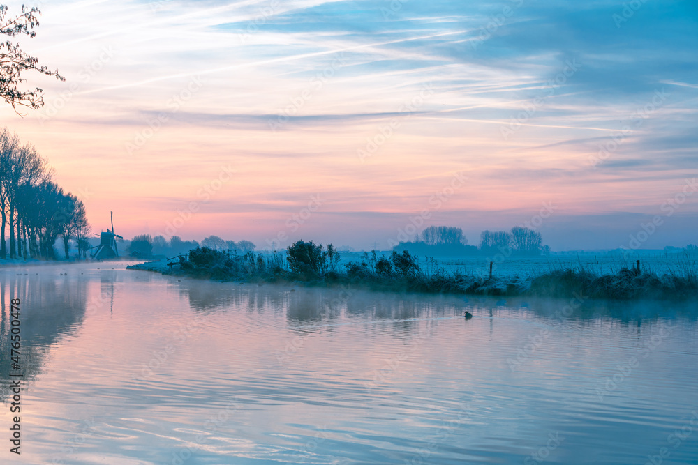 Φωτογραφία Sunrise over the river de Schie and the historical Hoogewegse mill on a cold morning in the South-Holland beach village of Noordwijk in the Netherlands