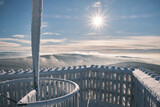 Lookout tower on top of the mountain with frosted railings and stairs. Mountain top with sun in the sky and fine clouds over the woods. Velka Destna in the Eagle Mountains, Czech republic.