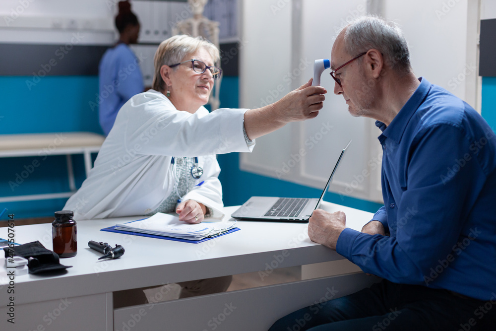 Specialist using thermometer to measure temperature of ill man, checking healthcare and flu symptoms. Woman doctor measuring fever of patient, using medical instrument at annual checkup visit. Specialist using thermometer to measure temperature of ill man, checking healthcare and flu symptoms. Woman doctor measuring fever of patient, using medical instrument at annual checkup visit.