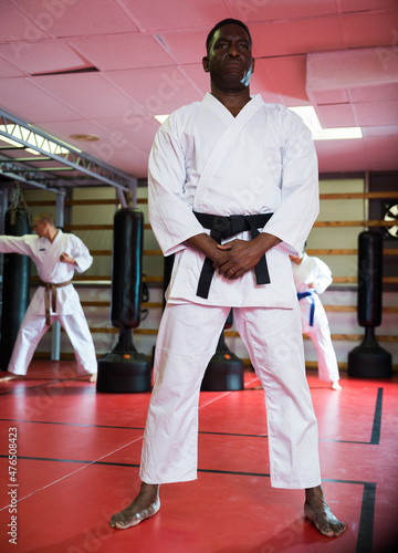 African-american man standing in gym during group karate training.