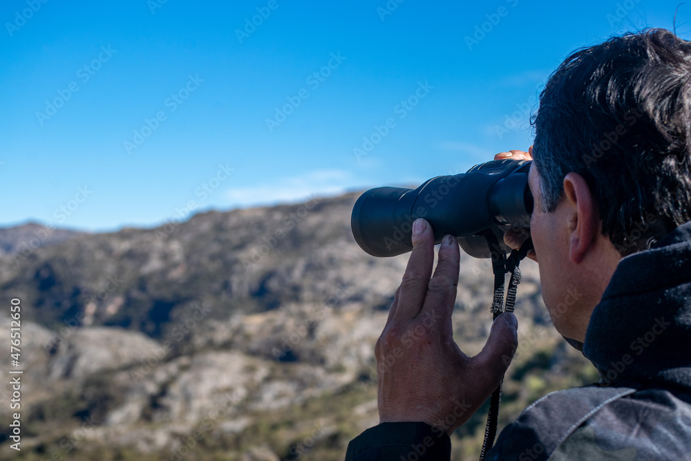 middle-aged man as an adult looking through binoculars while trekking