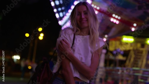 Young blonde woman models for camera at showground carnival at night. Handheld shot. photo