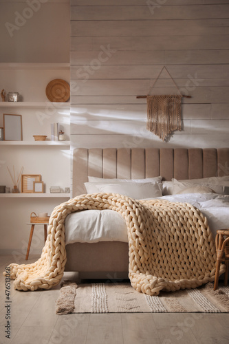 фотографія Soft chunky knit blanket on bed in stylish room interior