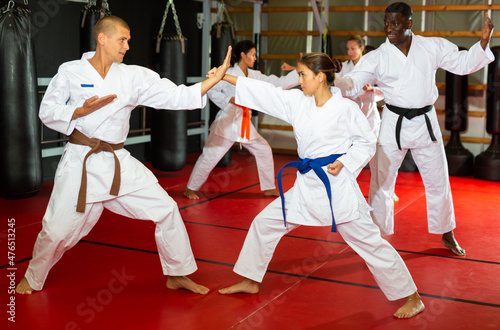 Man and woman in pairs exercising karate movements during group training