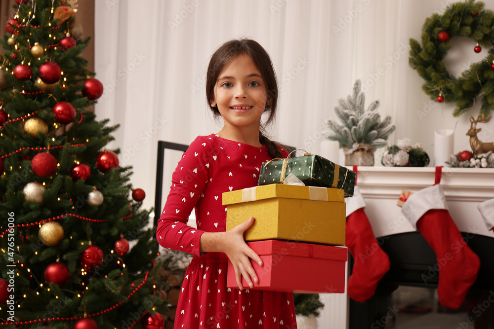 Cute child with gift boxes near Christmas tree at home Cute child with gift boxes near Christmas tree at home