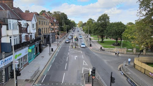 Cars passing crossroads and driving on street in residential borough on city outskirts. Woodford, London, UK photo
