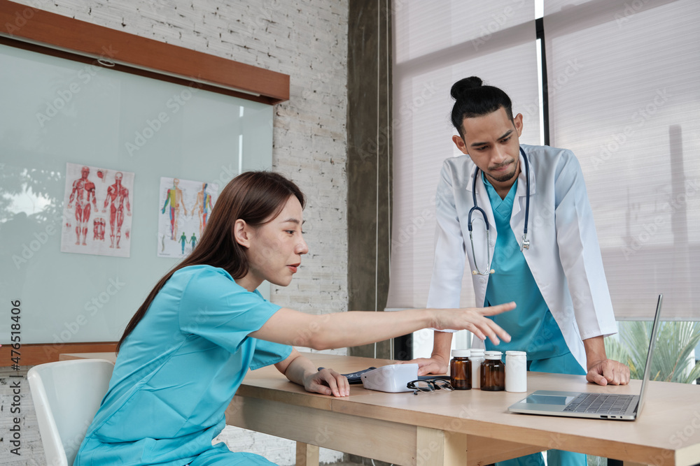 Obraz premium Healthcare team partners. Two uniformed young Asian ethnicity doctors are co-workers discussing medication in hospital's clinic office. Specialist persons are experts and professionals.