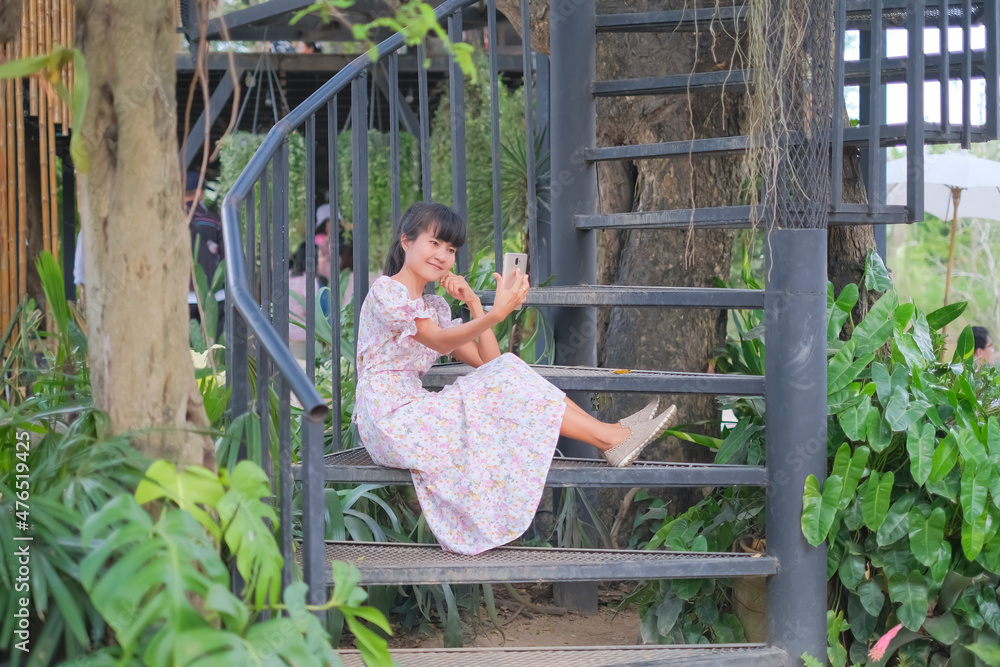 Obraz premium Woman smile and holding mobile smartphone for selfie. sit on the stairs. Technology for lifestyles. tourist vacation travel tropical in holidays concept.