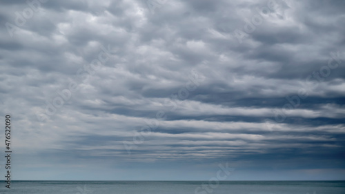 The space of the sky is closed to the horizon by rows of clouds. Moody weather on the seaside.
