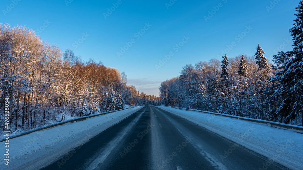 Country road among the winter forest covered with white snow.