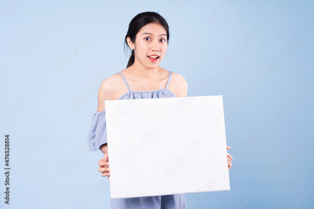 image of asian girl holding white board, isolated on blue background image of asian girl holding white board, isolated on blue background