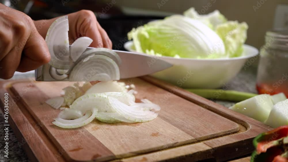 Slicing Fresh White Onions On Wooden Board With Chinese Cabbage Leaves In A Bowl In Background. close up Slicing Fresh White Onions On Wooden Board With Chinese Cabbage Leaves In A Bowl In Background. close up