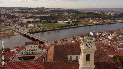 Aerial zoom in University's clock tower in coimbra cityscape drone view of the river and the bridge with Portugal flag photo