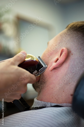 Young man in a barbershop. Getting the services of a hairdresser. Haircut and shave.