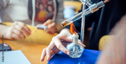 Students conduct experiments in chemistry class. Heating the test tube over the burner, close up.