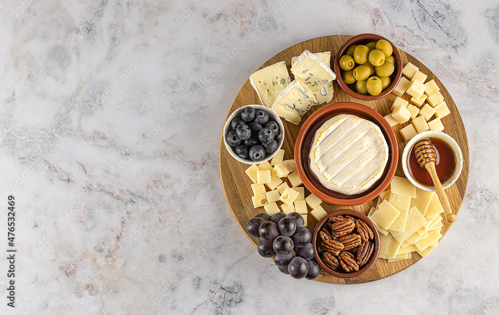 Top view of tasty charcuterie board with cheese, grape, nuts, olives, and ham on a circle kitchen plate Top view of tasty charcuterie board with cheese, grape, nuts, olives, and ham on a circle kitchen plate