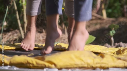 Close-up of a child's feet jumping high while playing in the yard on a small trampoline. Childrent playing trampoline in the playground. photo