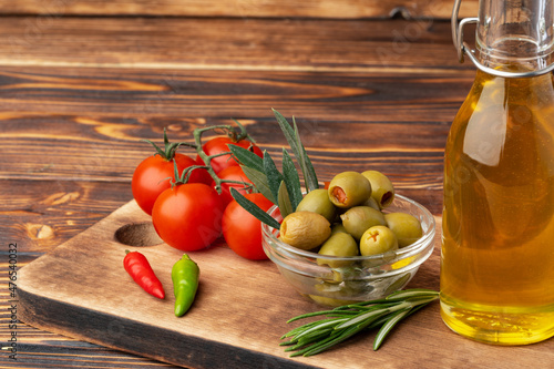 Olive oil, olives and tomatoes on wooden background