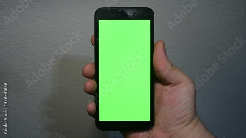 hand holding smart phone with green screen