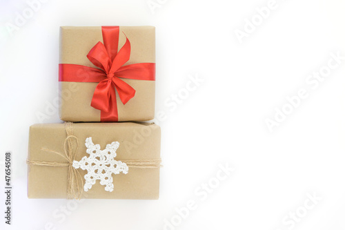 Christmas and New Years flatlay background. Gift box wrapped in kraft paper with jute cord. Decorated with a crocheted snowflake. Box with a red ribbon. Place for your text