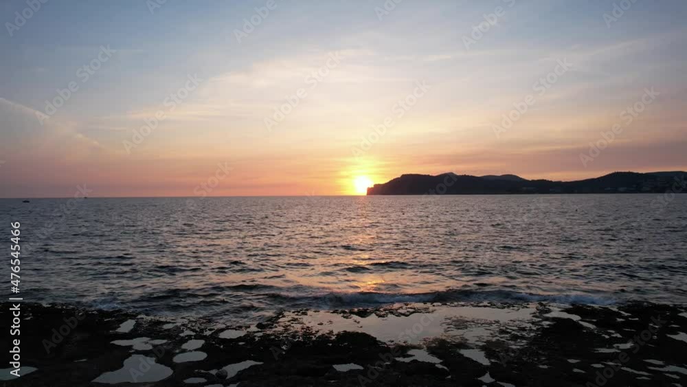 Mallorca island aerial view of the sunset over the sea with some high cliffes in the distance, boats on the water. Rocky beach of Mallorca. Aerial, drone view over the sea. Mallorca island aerial view of the sunset over the sea with some high cliffes in the distance, boats on the water. Rocky beach of Mallorca. Aerial, drone view over the sea.
