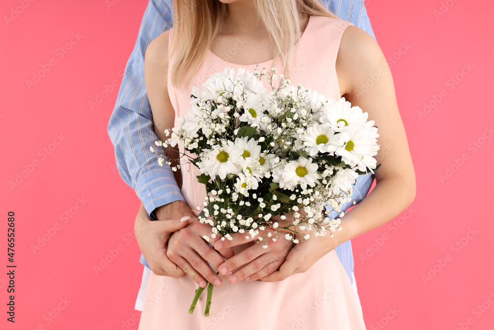 Cute couple with bouquet on pink background