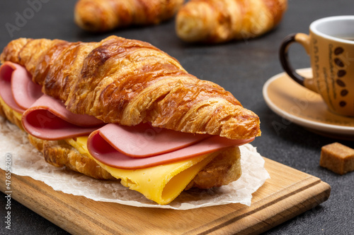 Croissant with ham and cheese on board.