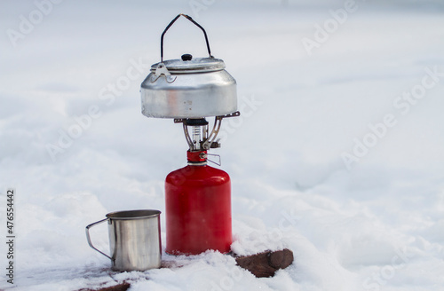 Picnic in winter. A kettle, a gas burner and a mug on a background of snow