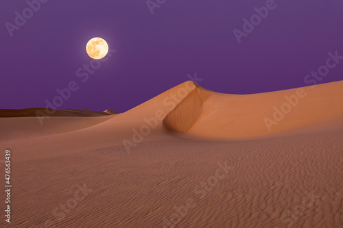 Fototapeta Naklejka Na Ścianę i Meble -  Full moon over the sand dunes in the desert. Arid landscape of the Sahara desert.
