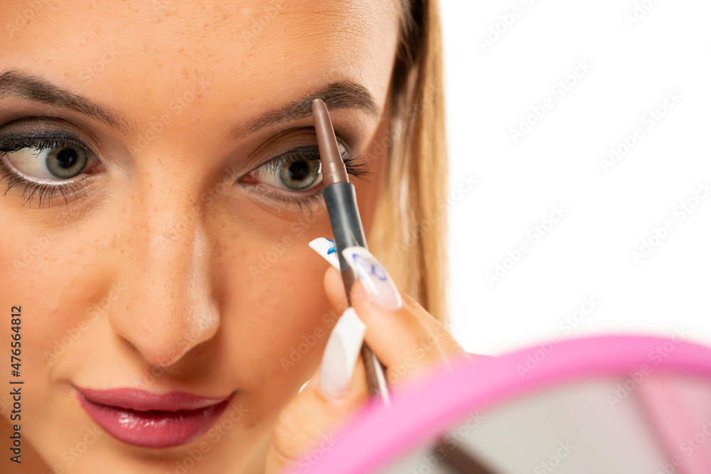 beautiful young woman shaping her eyebrows with a pencil