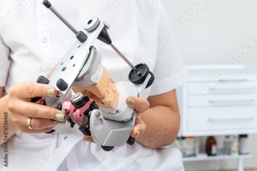 Dentist holding dental articulator with dental gypsum prosthesis model in dental laboratory photo