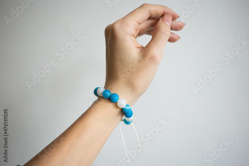 Bracelet with natural stones of different colors on a beautiful hand of a young girl on a white background