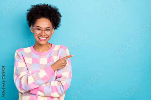 Portrait of attractive cheerful wavy-haired girl demonstrating copy space solution isolated on bright blue color background