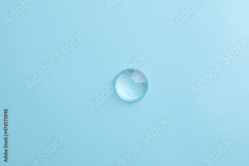 Drop of transparent ointment on light blue background, top view